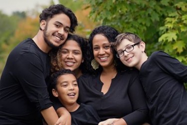 Five people all dressed in black standing and hugging each other