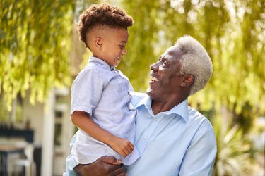 A person smiling at the child they are holding in one arm